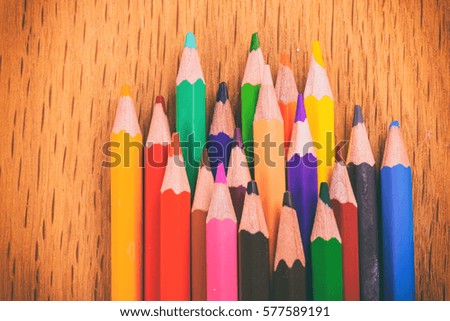 Multi-colored pencils on a wooden background