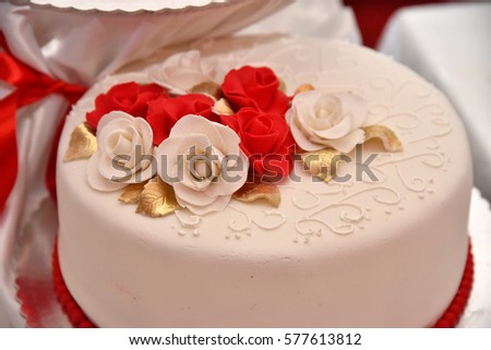Sweet cakes in the form of red roses decorate the wedding cake with more decorative twigs of white cream. Photographed at a wedding in Novi Sad, Serbia.