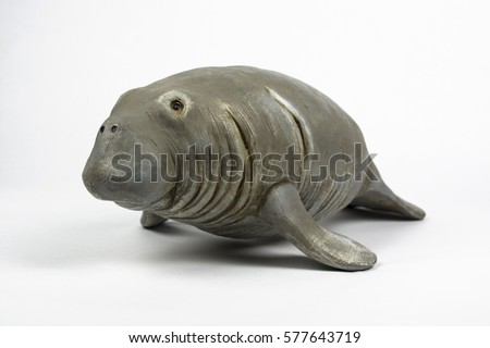A resin or wood figurine of a manatee, shown in a three-quarter view, isolated on a white background