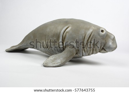 A resin or wood figurine of a manatee, facing toward the right.