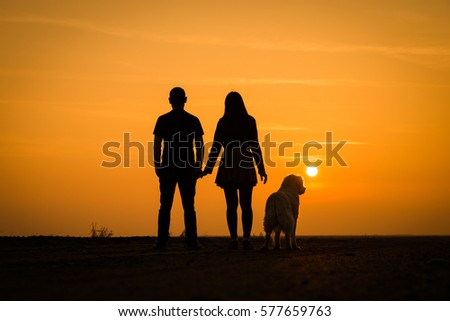 Silhouette lovers couple with dog on sunset dusk sky background. black shadow of people, hug and kiss, family: passion in love concept: decoration,design,valentines, family