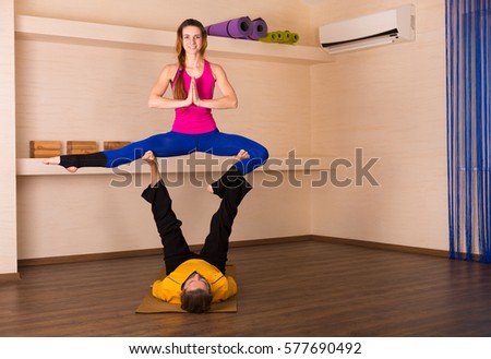 Man and a woman performing acrobatic yoga in a studio