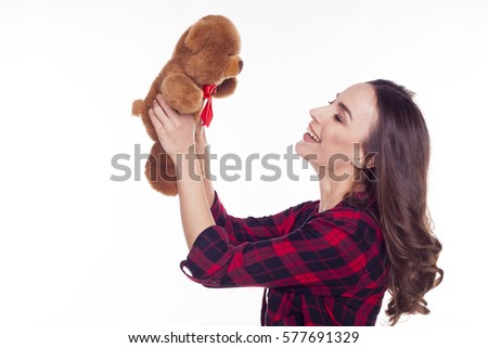 A gift from a loved one. Beautiful smiling young brunette girl with clean skin in a red checkered shirt holding a Teddy bear on a white background isolated. Celebration concept. With Love. 