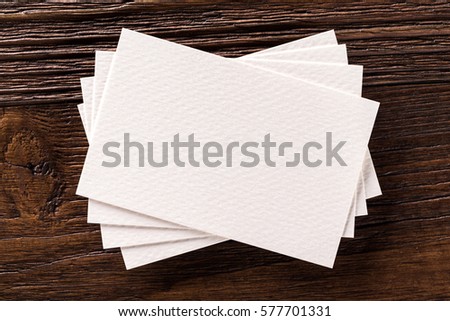 Mockup of business cards fan stack at textured brown wooden board background.