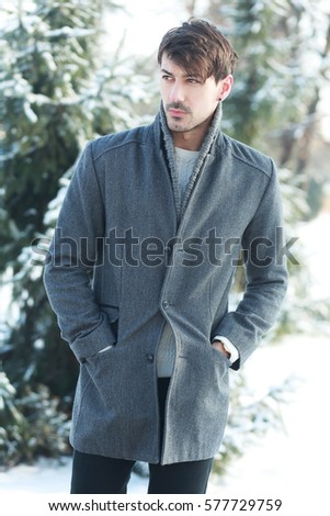 Outdoor portrait of smiling handsome man in coat and scurf. Casual winter fashion