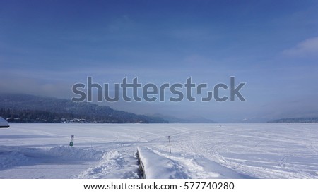 A picture of frozen Whitefish Lake with a frozen dock in the foreground.