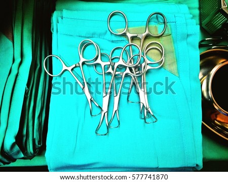 Surgical instrument; metal towel clips on green towel in operating room