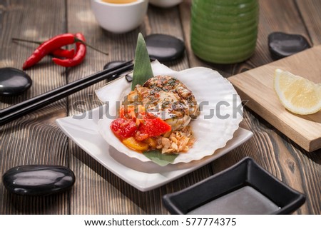 Fried seafood with vegetables and mashed potatoes on metal pan. Asian style picture with stones and chopsticks.