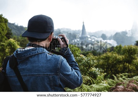 A guy in jeans jacket taking a photo on the mountain, in Chiang Mai Thailand