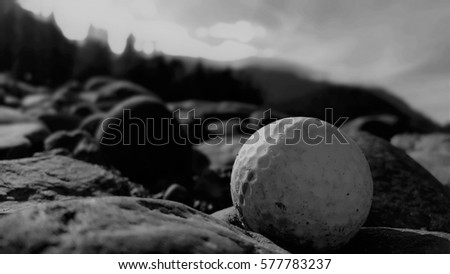 Black and white picture of golf ball on beach amongst rocks, Hope, BC