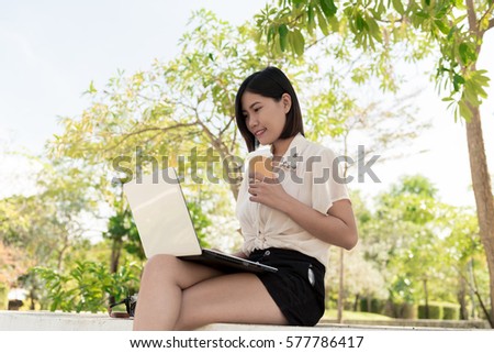 Portrait relaxation with a cup of coffee and tablet. Girl with laptop an coffee. Beautiful young woman with notebook sitting on the park.