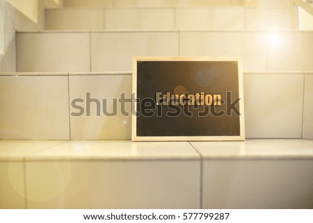 Black board on stairs with message "education". Lenses flare effect applied