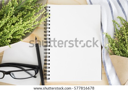 blank notebook on desk and bouquet flowers on table