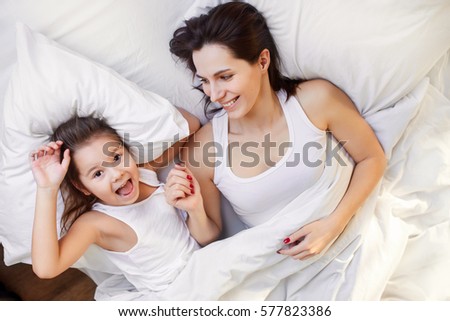 mom and little daughter having fun in bed at home
