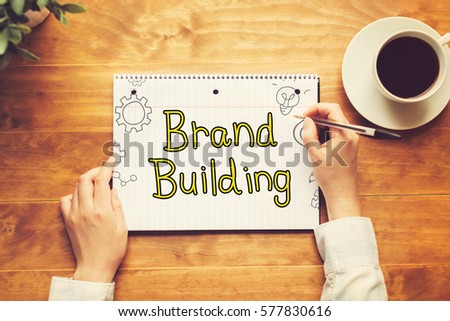 Brand Building text with a person holding a pen on a wooden desk
