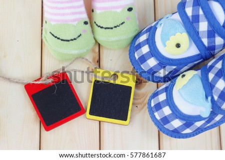Cute baby shoes and socks on wooden background. Copy space and background concept.
