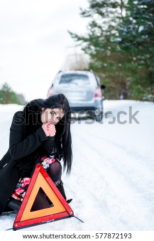 portrait of a beautiful young girl, whose car broke down in the winter woods. it collects warning triangle, and warms cold hands breathing