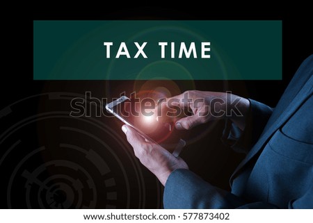 a business man touching a smart phone screen with flare on black background and text TAX TIME