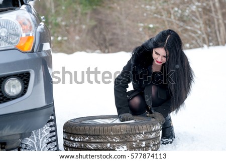 Fault car in the winter. Young beautiful girl trying to repair the car, engine repair