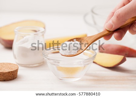 sea salt, starch in the jar, cut the potatoes into slices for recipes of cosmetics at home on a white wooden background Royalty-Free Stock Photo #577880410