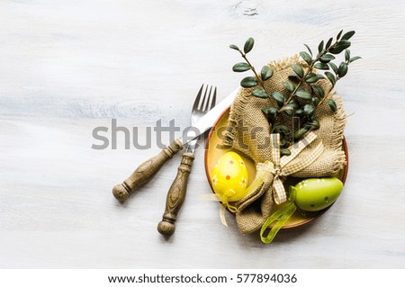Table setting for Easter dinner with tulips and eggs on rustic wooden table