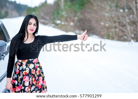 young beautiful woman signaling problems with broken  car on winter road