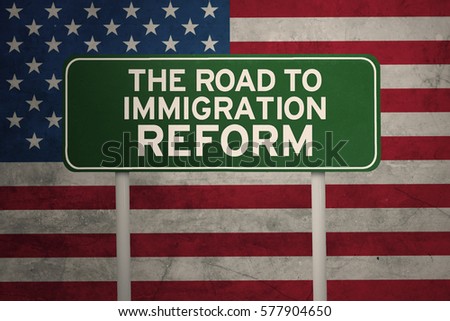 Picture of green sign road with text of the road to immigration reform and flag of United States in the background