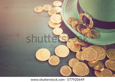 Happy St Patricks Day leprechaun hat with gold chocolate coins on vintage style green wood background,, with applied retro style faded filters.