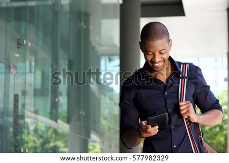 Portrait of male student walking in city with tablet and bag
