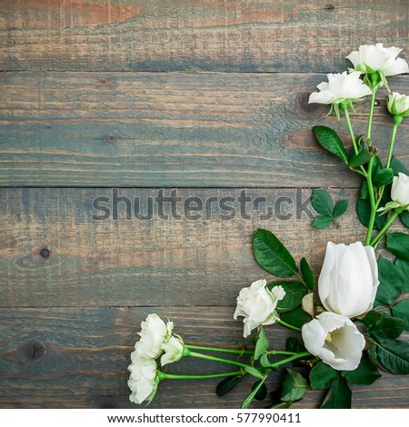 Floral background. Floral frame made white flowers and green leaves on wood background. Flat lay, top view.