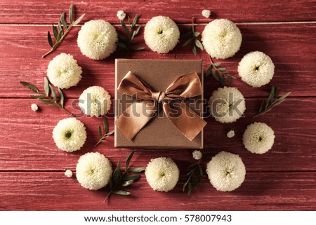 Gift box with flowers on wooden background