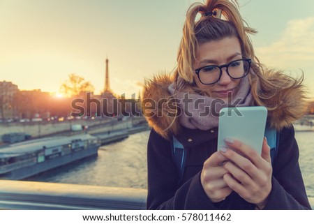 Using cellphone with Eiffel tower, Paris in the background.