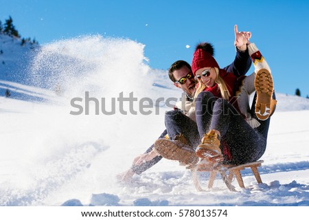 Young Couple Sledding And Enjoying On Sunny Winter Day