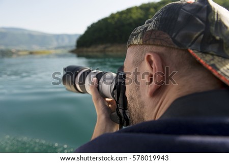 Photographer in nature taking pictures to a beautiful lake