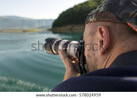 Photographer in nature taking pictures to a beautiful lake