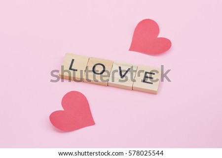 Text wooden blocks spelling the word love on pink background