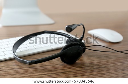 Modern headphones and wireless computer devices on wooden table
