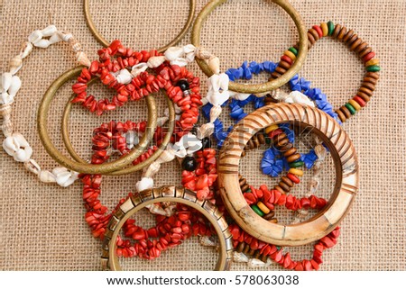Necklace made of natural stones and bracelets made of metal and bones on a background of burlap.