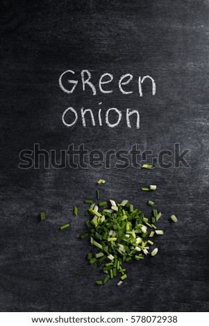 Top view picture of cut green onion over dark chalkboard background.