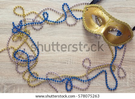 Mar di Gr as background with golden mask, beads and copy space. Carnival  mask on a wooden background. 