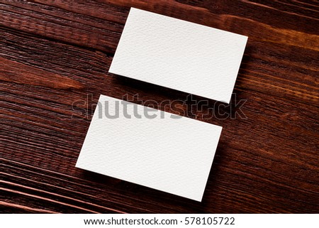 Closeup mockup of two blank horizontal business cards at brown wooden table background.