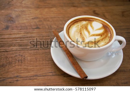 Cup of hot latte art with cinnamon coffee on wooden table   