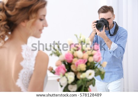 Wedding photographer taking photo of beautiful bride in studio