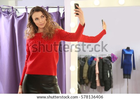 Beautiful young woman taking selfie in modern shop