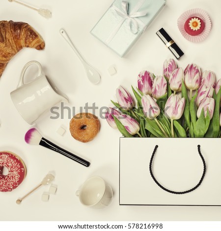 Top view of spring flowers, coffee, mobile phone, croissants, gift and cosmetics. Flat lay image. Holiday, romance of modern life concept