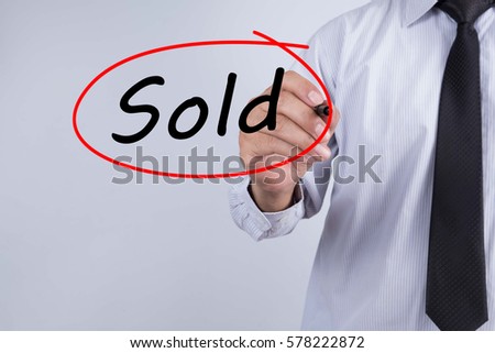 Businessman Hand Writing Sold with a marker over transparent board,  Business concept.