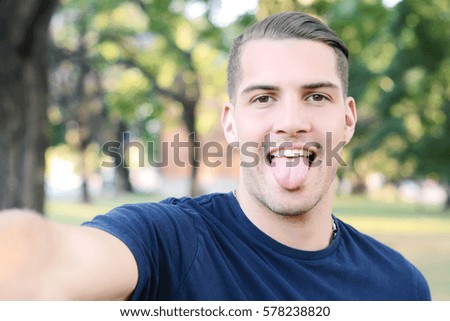 Young latin man taking a selfie in a park. Outdoors.