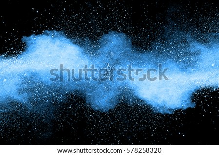 Abstract art blue powder on black background. Frozen abstract movement of dust explosion blue colors on black background. Stop the movement of blue powder on dark background.