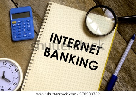 Business concept. Top view of table clock, calculator, magnifier, pen and notebook written INTERNET BANKING on wooden background.