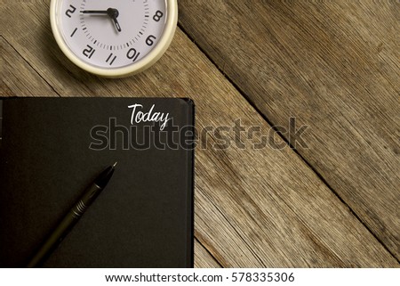Business concept. Top view of  table clock, pen and notebook written with TODAY on wooden background. Copy space. Flat lay.